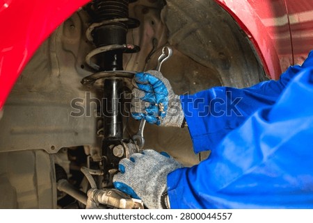 Unknown car mechanic inspecting and checking the shock absorber of customer  vehicle in auto repair shop