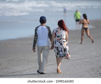unknown couple holding hands while at the beach