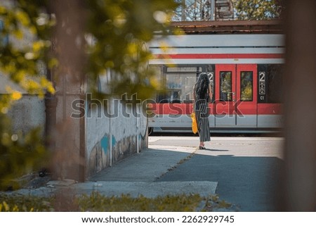 Unknown female viewed from behind is waiting to board a blue tram in the city of zagreb. Passengers of zagreb tramway system.
