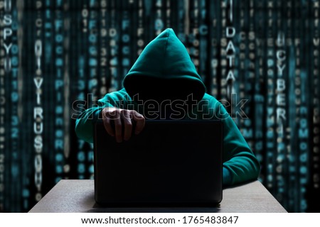 unknown hacker in the hood, closes the lid of the laptop, against the backdrop of a binary code
