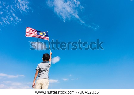 Unknown kid waving Malaysia Flag. Independence day and Merdeka Celebration. Blue sky and copy space.