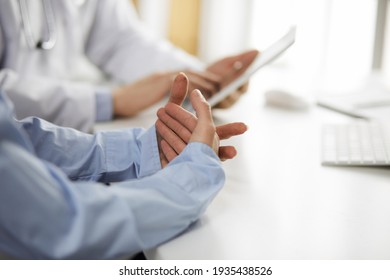 Unknown male doctor and patient woman discussing current health examination while sitting in clinic and using tablet computer, closeup of hands. Medicine and healthcare concept - Shutterstock ID 1935438526