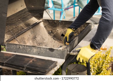 Unknown Man Cleaning Out Ashes From Charcoal Grill