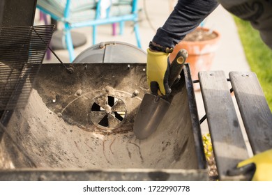 Unknown Man Cleaning Out Ashes From Charcoal Grill