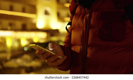 Unknown man in red jacket uses his smartphone. Winter evening