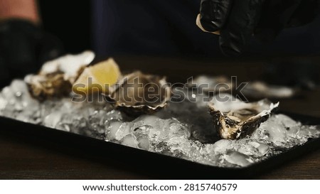 Unknown man squeezing lemon on seafood. Squeezing lemon juice onto the dish. Unrecognized male hands preparing mussels in shells with herbs, lemon and onion.