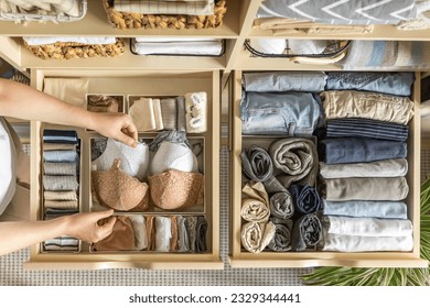 An unknown neat housewife lays out her underwear in the drawers of the wardrobe. The concept of organizing space and storing clothes. Top view. 
