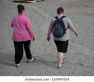 Unknown Overweight Couple Burning Calories As They Walk The Beach