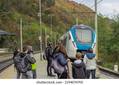 Unknown passengers are waiting at a train platform for a modern white and blue train to arrive to the station. Trbovlje, slovenia. - Shutterstock ID 2194074705