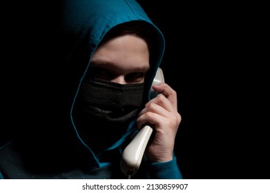 Unknown person with covered face makes an anonymous call intimidating and threatening the interlocutor - Shutterstock ID 2130859907