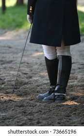 Unknown Rider With Long Horsewhip Standing On Ground.