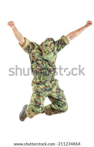 unknown soldier with hidden face in green camouflage uniform and hat jumping up in air with both hands raised above as sign of success