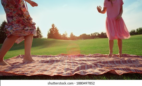 Unknown Woman With Daughter Jumping On Meadow In Slow Motion. Cheerful Mother With Cute Girl Holding Hands In City Park. Joyful Family Having Fun Outdoor.