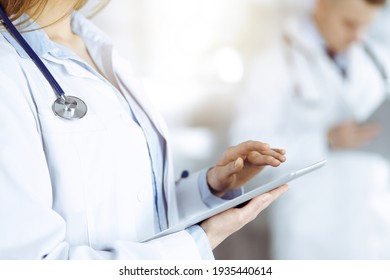 Unknown woman doctor is checking some data at computer tablet, close up. Young doctors at work in a sunny hospital. Perfect medicine and healthcare concept