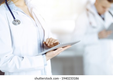 Unknown woman doctor is checking some data at computer tablet, close up. Young doctors at work in a sunny hospital. Perfect medicine and healthcare concept - Shutterstock ID 1940233186