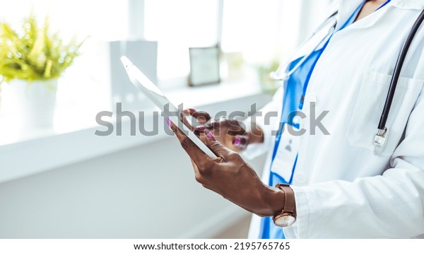 Unknown woman\
doctor is checking some data at computer tablet, close up. Young\
doctors at work in a hospital. Medicine and healthcare concept.\
Young doctor using digital\
tablet.