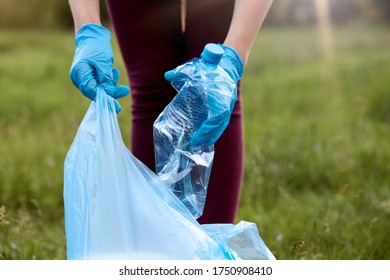 Unknown Woman Wearing Casual Trousers And Latex Gloves Picking Up Litter To Garbage Bag, Holding Used Plastic Bottle In Hand, Takes Care Of Planet, Cleaning Up Meadow.