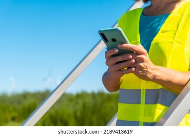 Unknown Woman Worker In A Wind Farm, Green Energy, Checking The Notes With The Phone