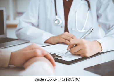 Unknown woman-doctor filling up an application form while consulting patient. Medicine concept - Shutterstock ID 1916373707