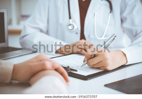 Unknown woman-doctor filling up\
an application form while consulting patient. Medicine\
concept