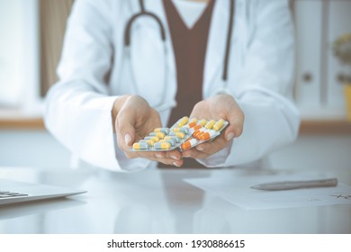 Unknown woman-doctor offering pack of different tablet blisters, close-up. Medicine concept