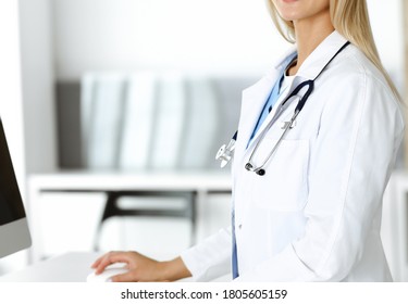 Unknown woman-doctor is typing on desktop computer at reception desk in clinic. Physician at work, close-up. Medicine concept - Shutterstock ID 1805605159