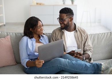 Unlimited Data. Excited African American Family Using Pc Notebook And Cell Phone At Home, Relaxing On Couch Together, Watching Movies, Browsing Internet, Chatting Online, Looking At Each Other