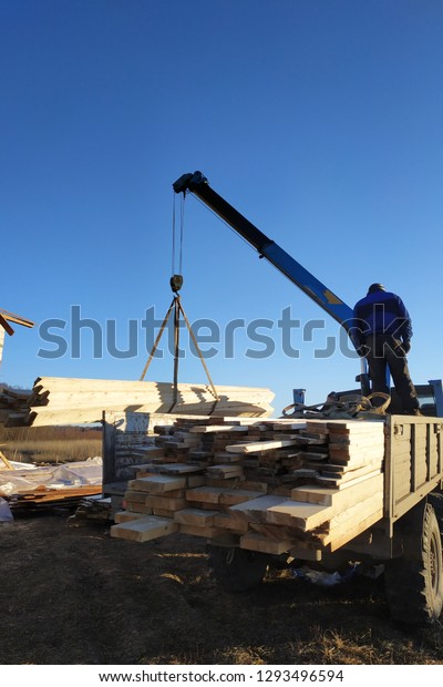 Unloading boards from the side of the crane with\
the help of people