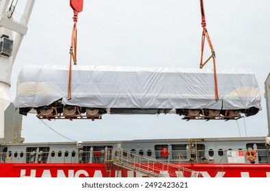 Unloading operation of project  cargo with port heavy lift cranes A crane on a large cargo ship docks loading a diesel-electric locomotive.  at Laem Chabang Port  