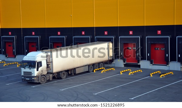 Unloading trucks at a modern warehouse\
complex. Logistics.