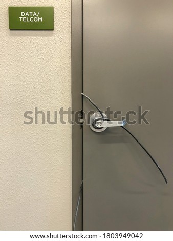 Unlocked service door to data and telecommunications closet of residential building, with end of one cable wrapped around door handle and another also protruding into hallway, for concepts of security Imagine de stoc © 