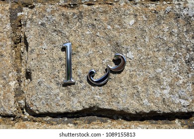 Unlucky House Number Thirteen On Weathered Stone With The Number Three Falling Away.