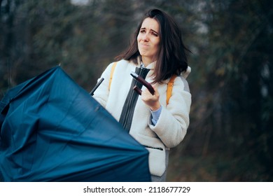 
Unlucky Woman Standing Outside With Broken Umbrella. Upset Woman Sitting In Bad Weather With No Real Protection From Rain And Wind
