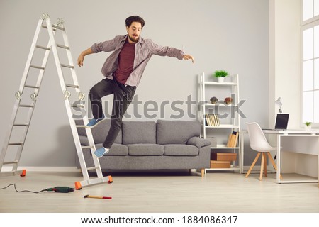 Unlucky young man has slipped from ladder while doing repairs and renovating house and is falling down on floor. Concept of getting hurt and injured in dangerous domestic accidents at home