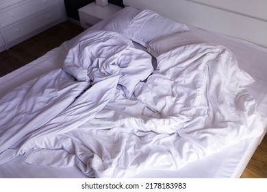 Unmade Double Bed With White Linens In The Morning