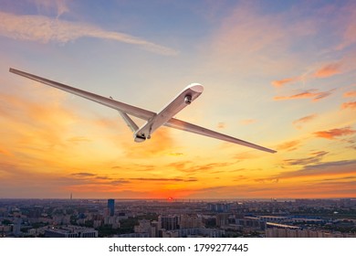 Unmanned Military Drone Uav Flying In The Air Over The City In Evening Sunset.