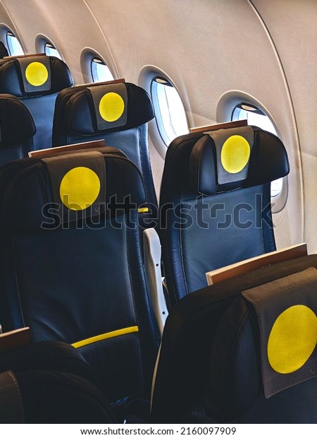 Unoccupied airplane seats, with\
a yellow circle on the headrest. Safety window to observe the\
landscape