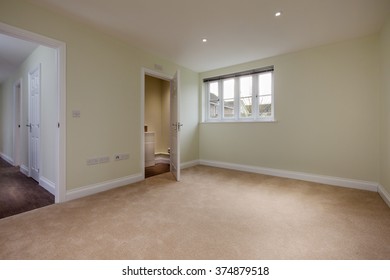 Unoccupied residential bedroom with water closet ensuite and doorway leading to hall - Shutterstock ID 374879518