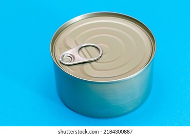 Unopened Tin Can With Blank Edge On Light Blue Background. Canned Food. Aluminum Can For Safe And Long Term Storage Of Food. Steel Sealed Food Storage Container