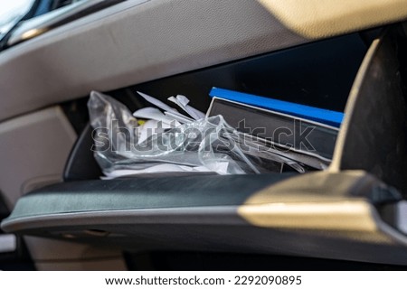 Unorganized mess inside an open glove compartment of a vehicle 