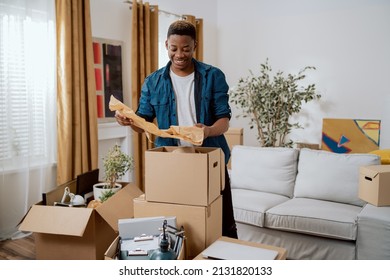 Unpacking cardboard boxes after moving, man cleans new apartment cluttered with things from previous home, looks at items, planning decorations, living room furnishings - Powered by Shutterstock