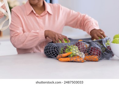 Unpacking fresh vegetables from reusable bag, person organizing groceries in kitchen. food, sustainable, healthy, green, lifestyle, shopping - Powered by Shutterstock