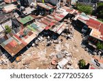 An unpaved open area littered with garbage in the center of an otherwise dense and cramped shanty town in Metro Manila.