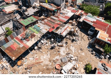 An unpaved open area littered with garbage in the center of an otherwise dense and cramped shanty town in Metro Manila.