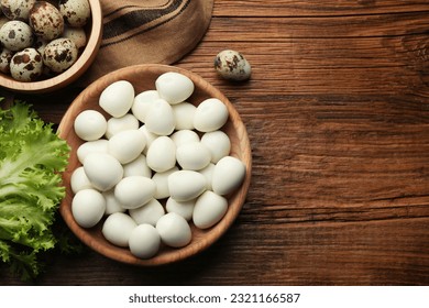 Unpeeled and peeled boiled quail eggs on wooden table, flat lay. Space for text