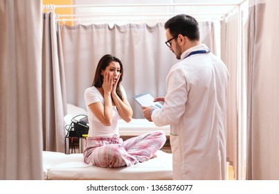 Unpleasantly surprised female patient listening prognosis. Doctor telling her news and holding tablet. - Shutterstock ID 1365876077