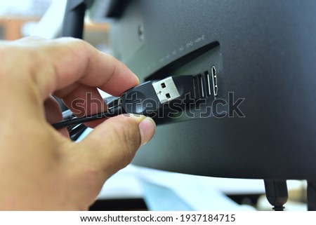 Unplugging USB cable from computer. Disconnect USB cord from the computer. Man hold USB plug against computer. [[stock_photo]] © 