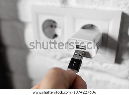 Unplugging USB cable from power adapter. Disconnect USB cord from the cellphone charger. Man hold USB plug against wall charger. Plug-in connector into european wall outlet or socket with AC adapter