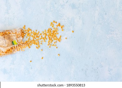 Unpopped corn kernals shot against a light blue textured background with space for text, copyspace, shot from above.  National Popcorn Day 19 January 2021