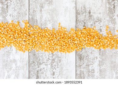 
Unpopped corn kernals shot against a light wooden background with space for text, copyspace.  National Popcorn Day 19 January 2021